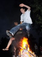 A young man and a girl jump over the fire