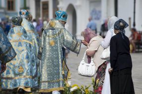 A woman kisses the hand of a priest