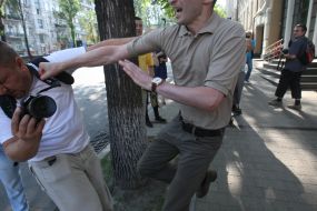 An employee of the Embassy of Georgia beats photojournalist