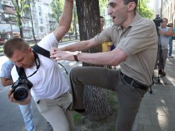 An employee of the Embassy of Georgia beats photojournalist