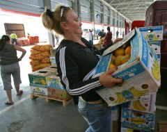A seller carries a box of melons
