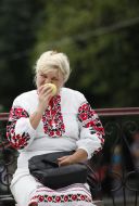 Woman in embroidered blouse eats an apple