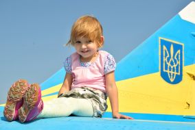 A girl sits on the wing of airplane