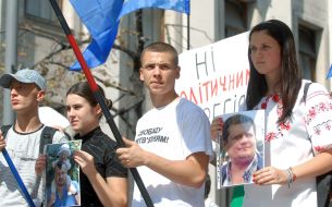 Участники акции держат фотографии политзаключенных