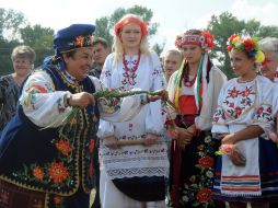 An elderly woman teaches girls to braid sheaves