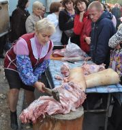 Жінка-продавець рубає тушу свині