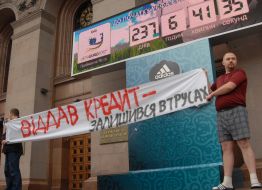 A young man in shorts holds a placard