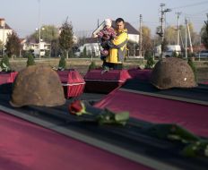 Мужчина с ребенком возле гробов с останками бойцов Красной Армии