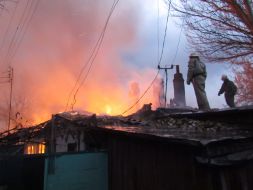 Пожарники осматривают крышу сгоревшего жилого дома