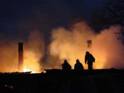 Пожарники осматривают крышу сгоревшего жилого дома