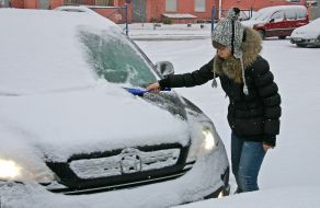 Девушка чистит автомобиль от снега