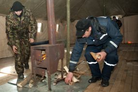 Сотрудник МЧС подбрасывает дрова в печь