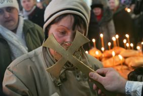 Віруюча жінка цілує хрест