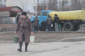 A woman carries buckets with water