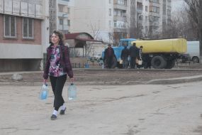 A woman carries buckets with water