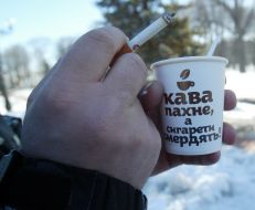 The man holds a cigarette and glass with coffee