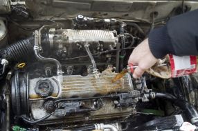 The participant of action washes the engine of car by carbonated water
