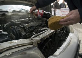 The participant of action washes the engine of car by carbonated water