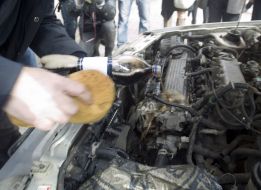 The participant of action washes the engine of car by carbonated water