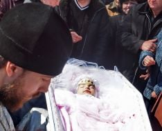 A priest near a coffin with Oksana Makar