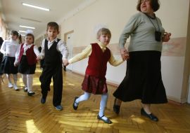 Воспитательница ведет слепых детей по коридору