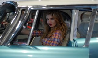 A girl sits after the helm of retro-car