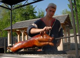 A man roasts pig on spit