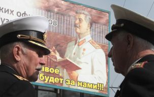 Veterans near a sandwich-board with the portrait of Stalin