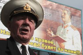 Officer near a sandwich-board with the portrait of Stalin