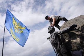 The former serviceman puts a blue beret on on a monument