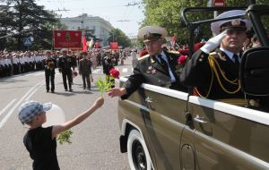 A boy gives flowers  to the veteran