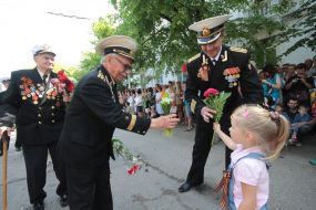The girl gives flowers to the participants of Parade of winners