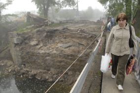 Женщина проходит возле разрушенного моста