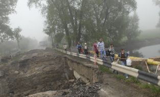 Люди идут возле разрушенного моста
