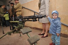 A boy stands near the machine gun