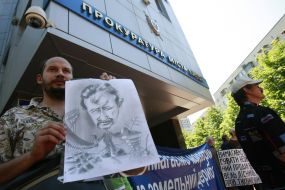 The participant of action holds a picture with depicts Aleksandr Popov 