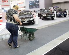 Жінка з візком проїжджає біля автомобілів 