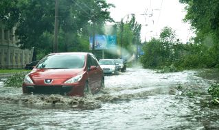 Cars drive on flooded street