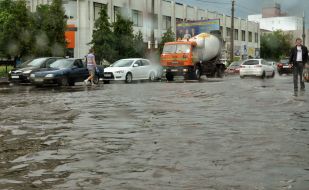 Cars drive on flooded street