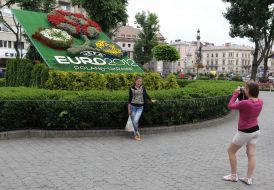 The girl is photographed near flower beds with the logo of Euro 2012