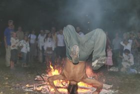 A fellow stands on a head near a fire
