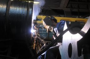 Сварщик варит вал турбины