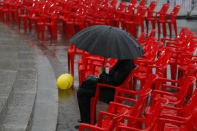 A man sits under an umbrella