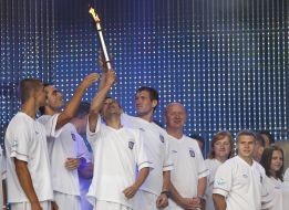 Athletes hold the torch with the Olympic flame