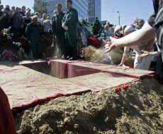 Люди кидають землю в могилу