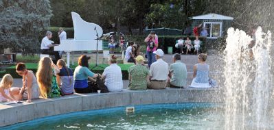 Отдыхающие слушают игру на белом рояле