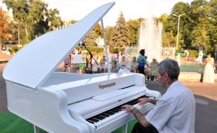 Музыкант играет на белом рояле