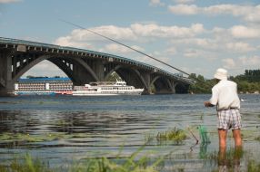 Рыбак ловит рыбу возле моста Метро