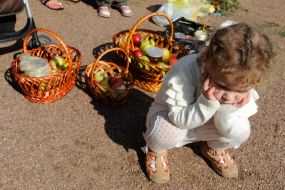 Маленькая девочка сидит возле корзинок с фруктами 