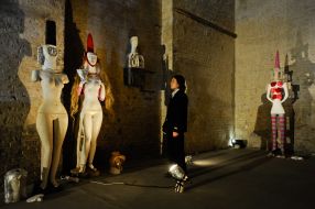 Посетитель рассматривает инсталляцию в виде обнаженных женщин 